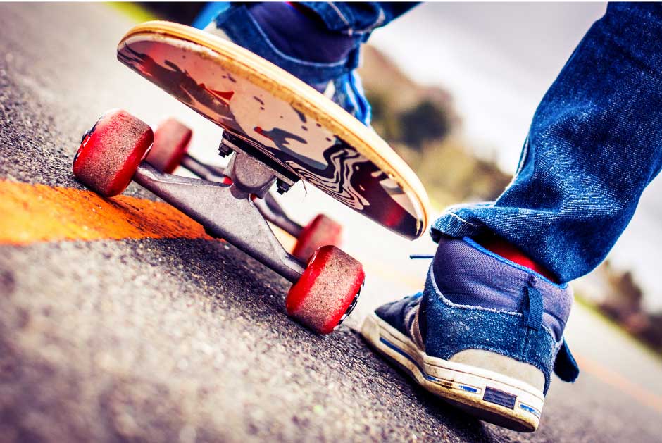 person in jeans and blue shoes riding a skateboard on pavement